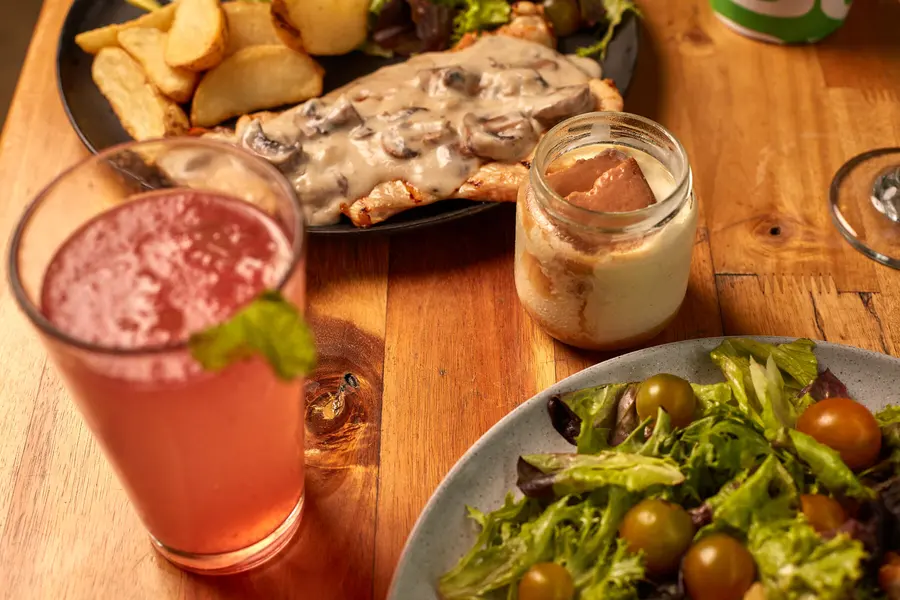 Mesa de SLOU con pollo, ensalada y bebidas