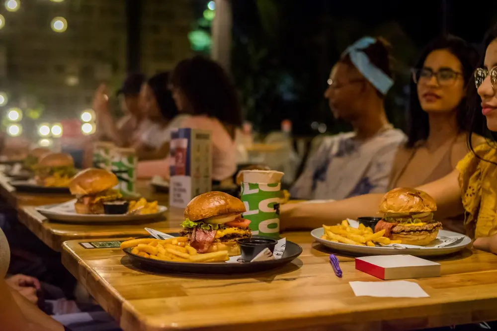 Amigos comiendo burgers en la mesa de SLOU